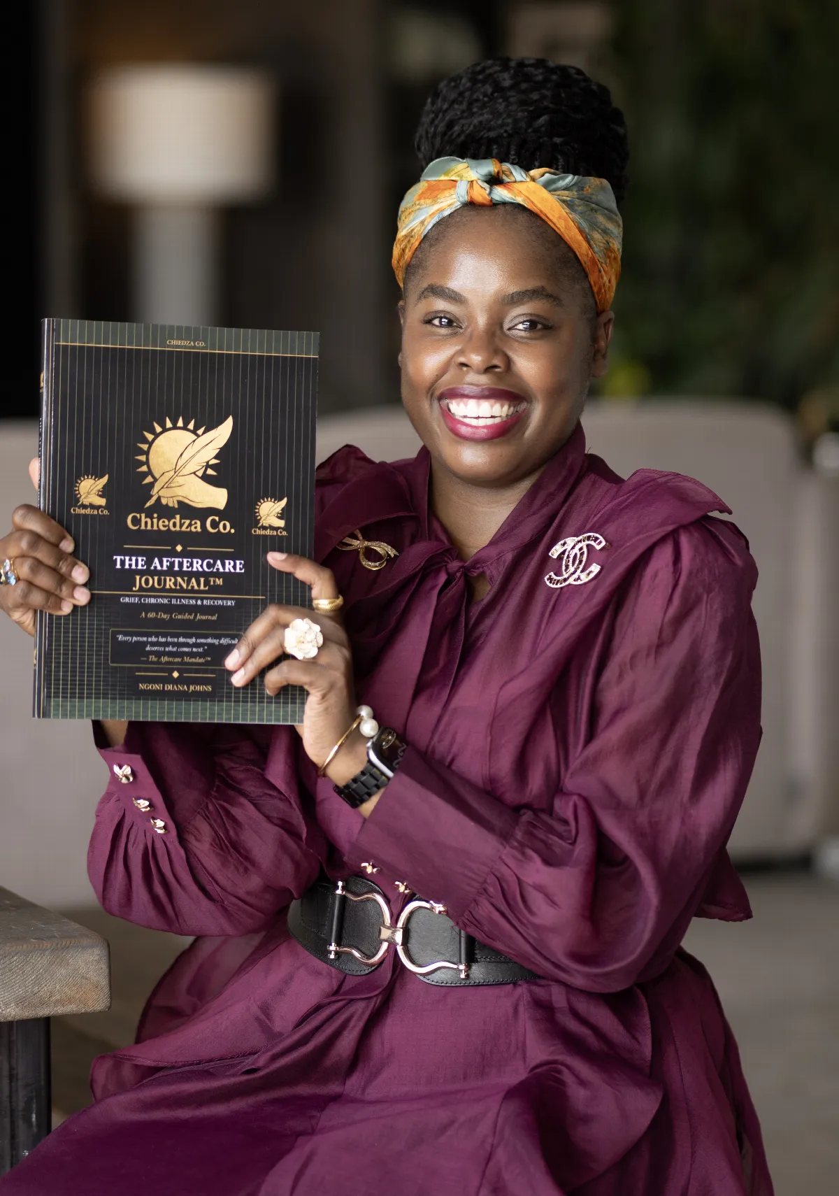 Ngoni Diana Johns holding a copy of The Aftercare Journal by Chiedza Co.